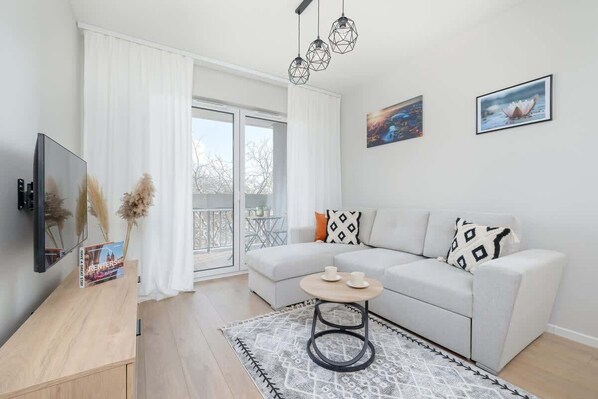 A bright living room with a cozy sofa, a coffee table, and a large window.