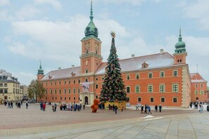 A scenic view of the Royal Castle in Warsaw's Old Town with a Christmas tree in the square.

