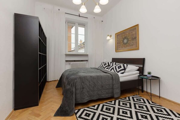 A cozy bedroom with a double bed, monochrome geometric bedding, and a wardrobe with mirrored doors.


