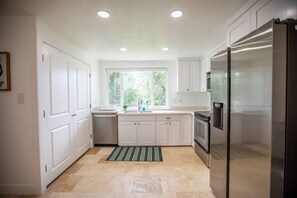 Open kitchen equipped with a fridge, sink, oven, and stove.