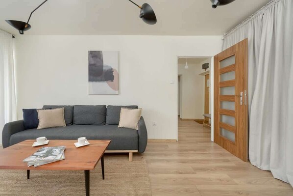 A modern living room with a dark sofa, a wooden coffee table, and a TV.