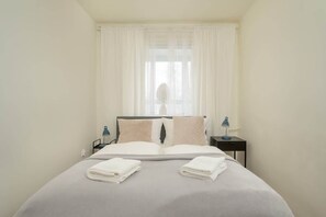A cozy bedroom with a double bed, white linens, and soft lighting.