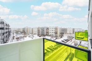 A balcony view overlooking a modern residential complex with green outdoor elements.
