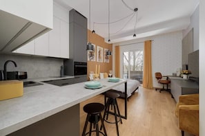 A contemporary kitchen with a sleek island counter, high stools, and minimalist design elements.