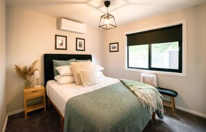 The elegantly appointed second bedroom includes a queen bed with side table and reading lamp.