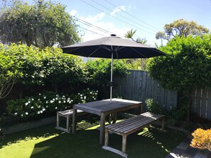 North facing sun drenched front patio with BBQ table and outdoor umbrella