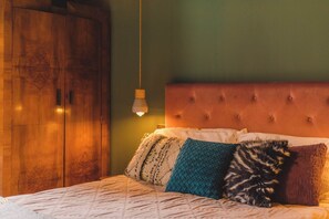A sophisticated bedroom with an earthy green wall, a plush bed, and soft lighting for a cozy feel.