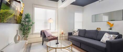 Comfortable sofaExperience comfort in a living room with plush sofas, a wide mirror, and a sleek TV setup.