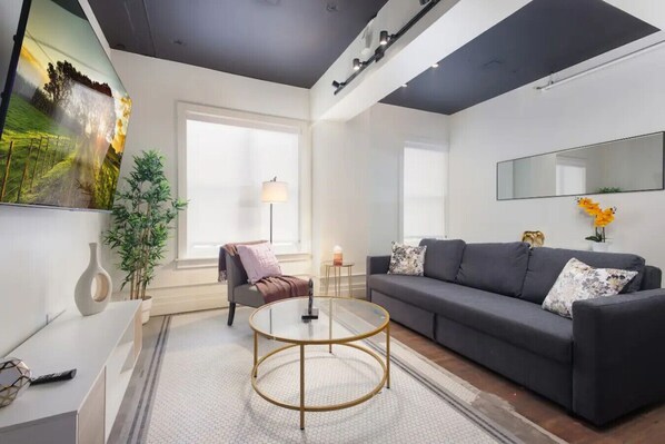 Comfortable sofaExperience comfort in a living room with plush sofas, a wide mirror, and a sleek TV setup.