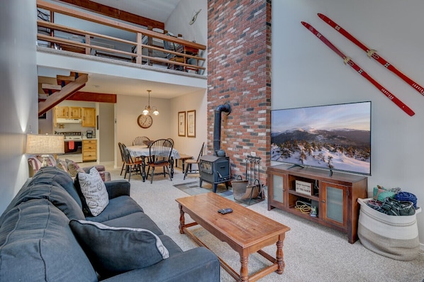 Open den area with a wood stove, large TV and a comfy sofa