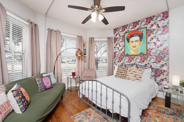 "Wake up to modern comfort in this chic bedroom, featuring eclectic vibes and a bold Frida Kahlo painting. Enjoy airy elegance with clean lines and natural light—sleep in style!