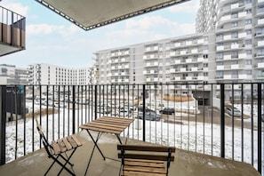 A balcony with outdoor seating and a view of contemporary apartment buildings, perfect for relaxation.