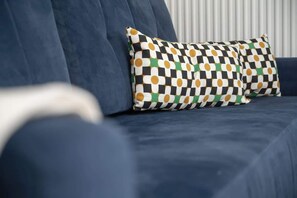 Close-up of a blue sofa with a geometric-patterned pillow, adding a touch of color and style.