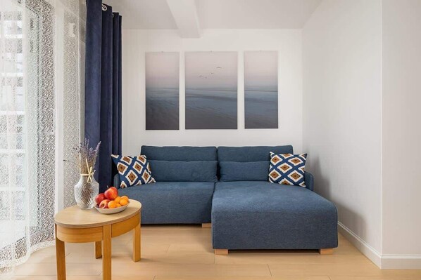 A cozy living room with a blue sofa, patterned cushions, and a wooden coffee table, creating a comfortable and stylish seating area.

