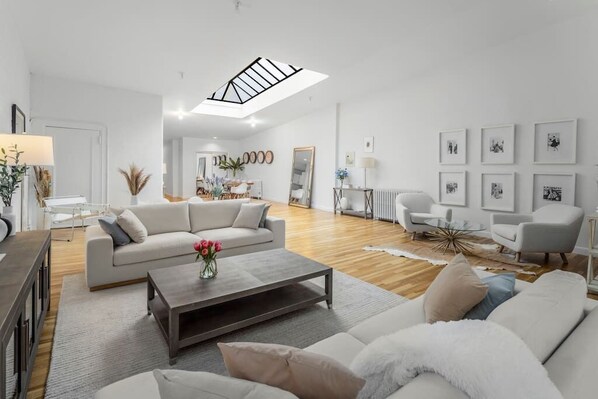 A living room with a skylight, multiple seating areas, and more in this massive floor through loft.