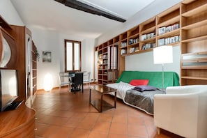 Living room with Smart HD TV, sofa bed, crystal table, leather chairs, library.