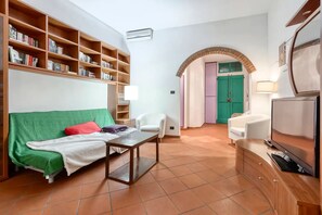 Living room with Smart HD TV, sofa bed, crystal table, leather chairs, library. 