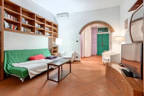 Living room with Smart HD TV, sofa bed, crystal table, leather chairs, library.