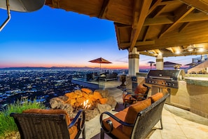 Outdoor kitchen & firepit under covered patio area w/ breathtaking city views