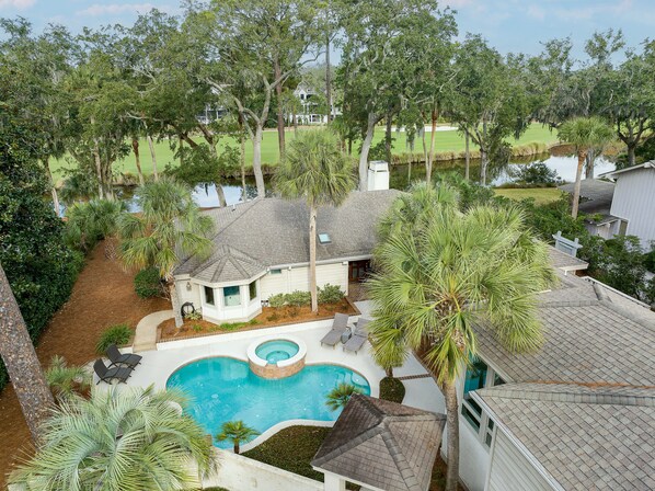View of front of house with pool and spa; Lagoon and golf course can be seen in the backyard