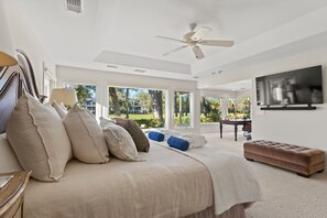 Primary bedroom on left side of house with king bed, TV, office, private attached bathroom and views of lagoon and golf course