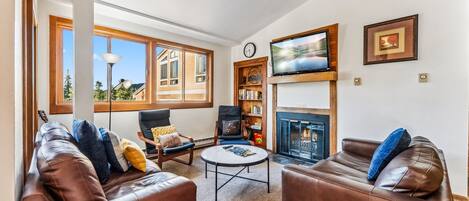 Living Room: 2 leather couches, 2 chairs, fireplace, TV, board games