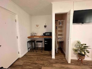 Kitchenette with coffee maker, microwave, mini fridge, coffee cup, wine glasses and silverwares.