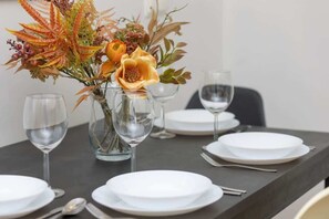 A beautifully set dining table with elegant glassware and autumn-inspired floral arrangement, perfect for a cozy meal.

