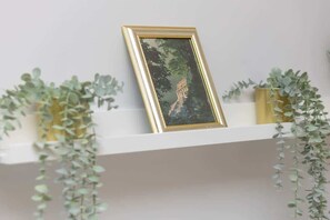 A decorative shelf with green plants and a gold-framed picture, adding a touch of elegance and freshness to the interior.


