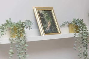 A decorative shelf with green plants and a gold-framed picture, adding a touch of elegance and freshness to the interior.