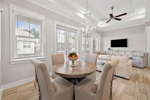 An open and airy design featuring a cozy dining area leading to the living room.