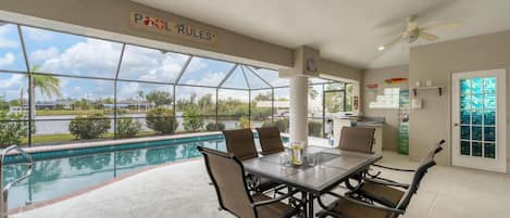 Spacious outdoor area with dining table overlooking the pool & canal