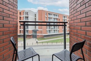 A balcony view with outdoor seating and a brick wall backdrop, perfect for relaxing and enjoying the neighborhood view.
