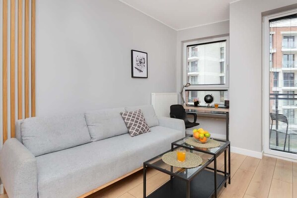 A modern living room with a light gray sofa, minimalist decor, and a glass coffee table, creating a bright and cozy atmosphere.
