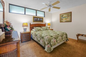 A cozy bedroom featuring a wooden bed frame with floral bedding, matching nightstands, and soft lighting. Ideal for relaxing in a serene setting.