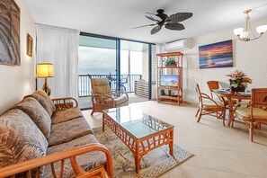 A tropical-inspired living room showcasing rattan furniture and ocean views from a private balcony. The perfect setup for indoor-outdoor relaxation.