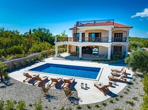 Sorgfältig dekorierter Garten mit geräumiger Terrasse mit Pool und Liegestühlen in einer haustierfreundlichen Villa in Krk