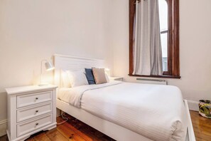 The bedroom is a calming haven with flowing curtains, a cosy queen bed and warm side lamps.  
