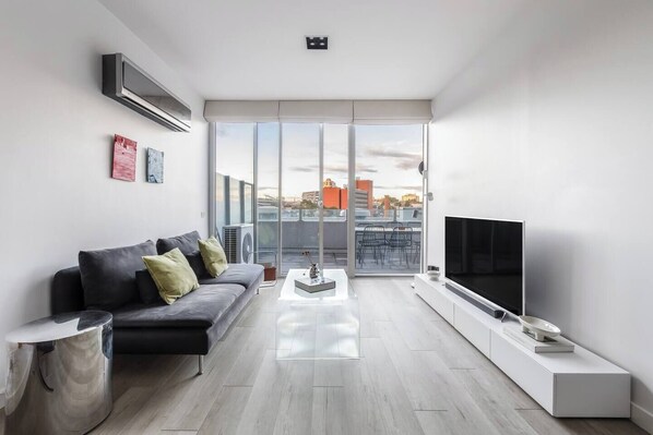 The living room has wall-to-wall glass doors that let in soothing sunlight. When you want to watch a movie on the HD TV, you can easily pull down the shades.