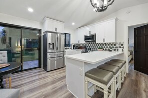 Kitchen with bar stool seating for 4 and sliding door to the backyard