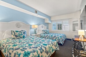 Coastal-inspired bedroom featuring two comfy queen beds with premium linens. Unwind with a Smart TV, free Wi-Fi, and relaxing beachy vibes, ideal for recharging after a fun-filled day by the shore. Styled for comfort and serenity.