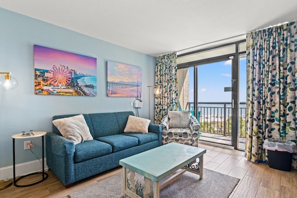 Oceanview Living Room with Sleeper Sofa: Unwind in a cozy living space featuring a sleeper sofa and direct access to your private oceanfront balcony. Enjoy sweeping views of North Myrtle Beach and easy access to beachfront pools at this tropical resort.