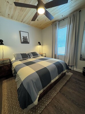 Unwind in a serene queen bedroom with a wood ceiling and bright windows