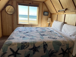 Wake up to stunning ocean views from this charming wood-paneled bedroom.