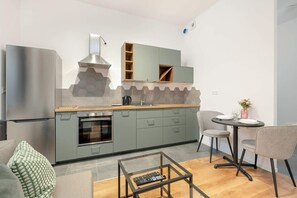 A modern kitchen with light grey cabinets, built-in appliances, and a small dining area with a round table and two chairs.
