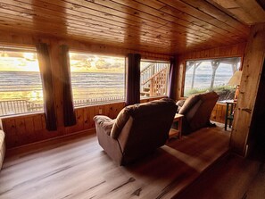 Cozy living room with ocean views and warm wood-paneled walls
