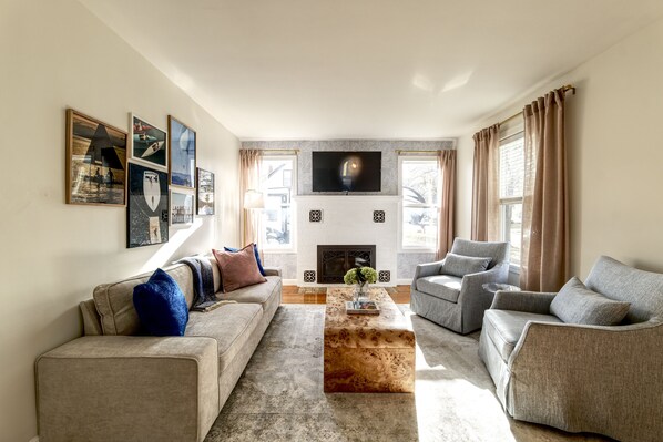 Living room with plush and large couch, with fireplace and tv mounted above