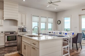 Modern coastal kitchen with ocean views, stainless steel appliances, and a spacious island—perfect for group meals and morning coffee