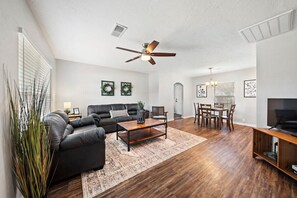 Experience the perfect blend of warmth and comfort in this well-appointed living room with classic hardwood floors and a functional ceiling fan ✨