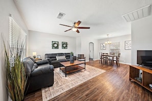 Experience the perfect blend of warmth and comfort in this well-appointed living room with classic hardwood floors and a functional ceiling fan ✨